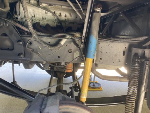 2015 Ford F-550 - Underside view of a truck chassis showing the engine, exhaust system, suspension components including a yellow and blue shock absorber, and…