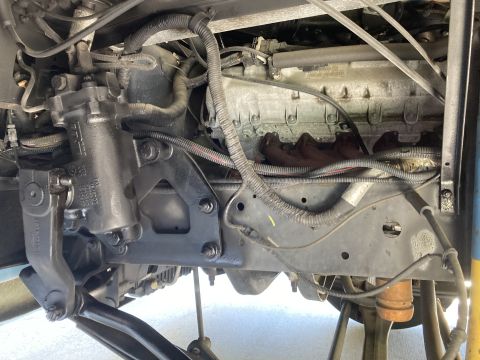 2015 Ford F-550 - A close-up view of the steering and engine components of a heavy-duty truck, showing the steering gear, exhaust manifold, and various hoses…