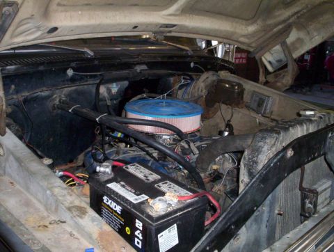 1978 Ford Bronco - The engine bay of a vehicle is viewed from above with the hood open, revealing various engine components.