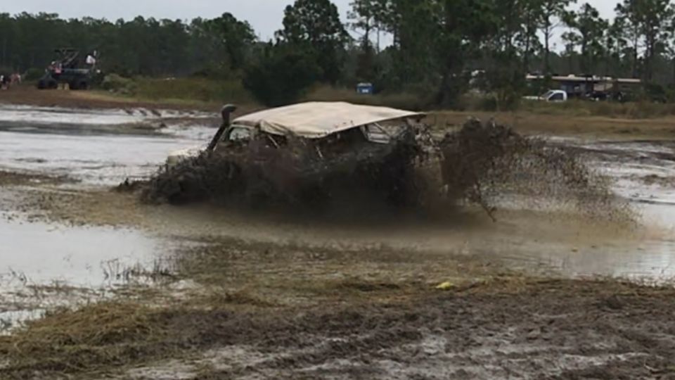 Off-road vehicle stuck in deep mud, splashing mud.