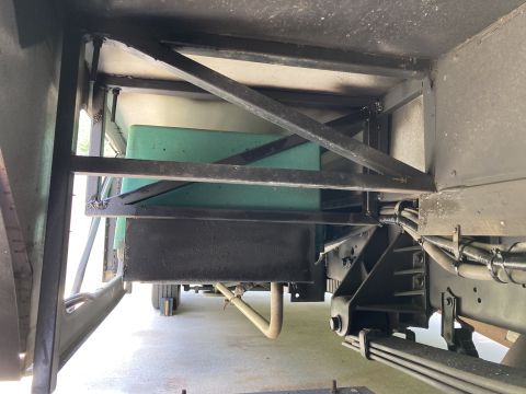 2015 Ford F-550 - The underside of a vehicle shows a green tank mounted to a black metal frame, with various hoses and suspension components visible.