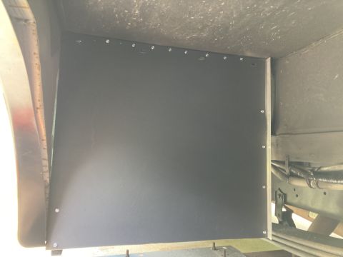 2015 Ford F-550 - A black panel is installed on the underside of a vehicle, likely a truck or RV, secured by multiple small rivets. The panel covers the whee…