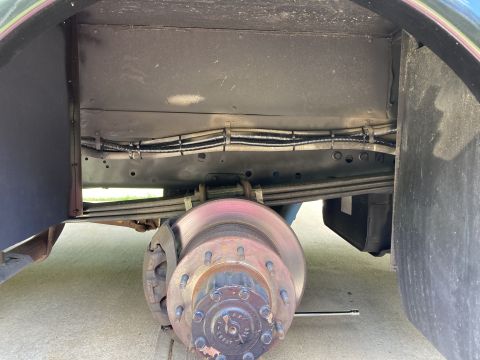 2015 Ford F-550 - A close-up view of the underside of a vehicle, focusing on the suspension, brake rotor, and wiring harness above the leaf springs. The vehi…