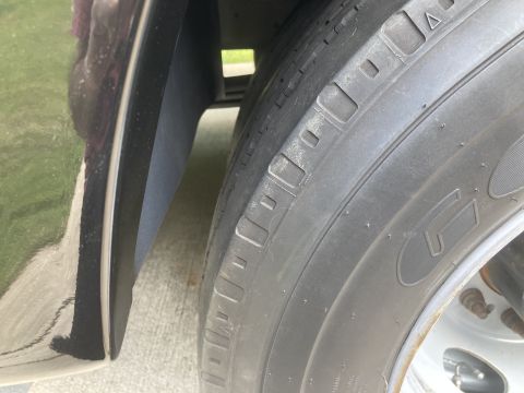 2015 Ford F-550 - Close-up view of a large truck tire and fender liner, showing tread detail and the edge of a dark-colored vehicle body.