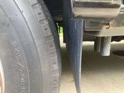 2015 Ford F-550 - A close-up side view shows the tread of a tire next to a black mud flap and part of the vehicle's undercarriage, including exhaust pipes.