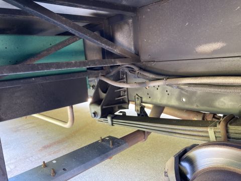 2015 Ford F-550 - The underside of a vehicle shows the rear suspension system, including leaf springs, U-bolts, and a portion of the driveshaft. A brake roto…