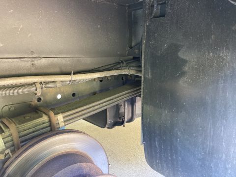 2015 Ford F-550 - The underside of a vehicle shows a leaf spring suspension system and a brake rotor. Wires and hoses are routed along the frame above the su…