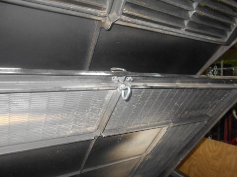 1992 Ford Bronco - Close-up view of a black metal latch mechanism connecting two angled panels, likely part of a vehicle's hood or trunk.