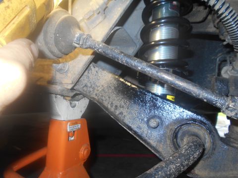 1992 Ford Bronco - A close-up view shows the suspension components of a vehicle, including a shock absorber, control arm, and a jack stand supporting the fram…