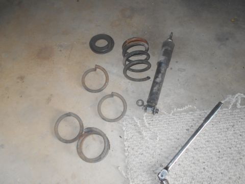 1992 Ford Bronco - A disassembled suspension system for a 1992 Ford Bronco is laid out on a concrete floor. The parts include a shock absorber, a coil spring,…