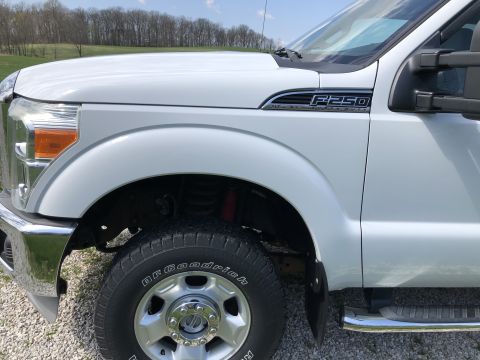 2011 Ford F-250 - The front fender and tire of a white Ford F-250 Super Duty pickup truck are shown in a close-up, side-view shot. The BFGoodrich tire and ch…