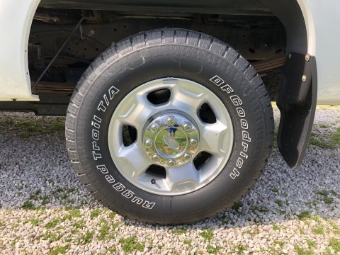 2011 Ford F-250 - A close-up view of the front passenger side wheel and tire of a white pickup truck. The tire is a BFGoodrich Trail T/A Radial with white le…