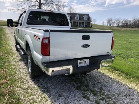 2011 Ford F-250 - The rear passenger side of a white Ford F-250 Super Duty pickup truck is shown parked on a gravel driveway. The truck has FX4 Off-Road badg…