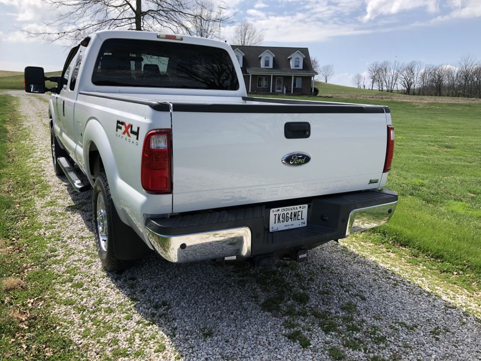 White Ford F-250 Super Duty pickup truck, rear passenger side view, FX4 Off-Road badging, Indiana license plate