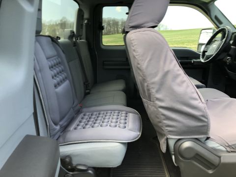 2011 Ford F-250 - Interior view of a pickup truck's rear and front passenger seats, featuring gray seat covers with a textured pattern on the rear seat cushi…