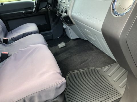 2011 Ford F-250 - The interior of a Ford Super Duty pickup truck shows the front passenger seat and dashboard area. Gray seat covers are installed over the o…