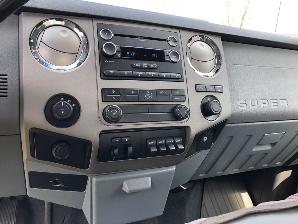 Interior dashboard of a Ford Super Duty truck showing the radio, climate controls, and 4x4 shifter.