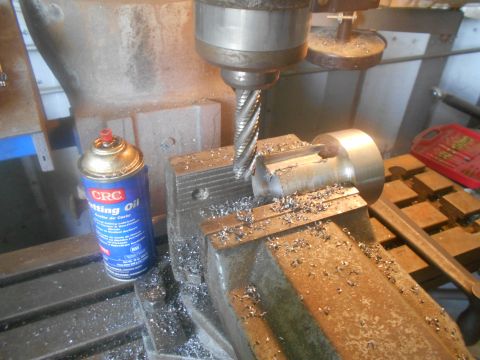 1992 Ford Bronco - A metal milling machine is cutting a piece of metal. A can of CRC cutting oil is visible next to the workpiece.