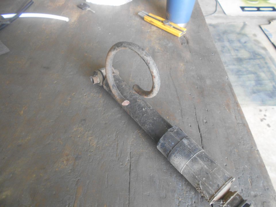 Black shock absorber with curved spring on weathered wood surface