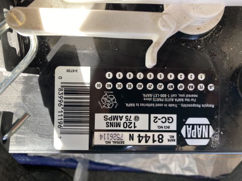 2015 Ford F-550 - A close-up, top-down view of a NAPA GC-2 battery, showing its label with specifications and a barcode. The battery is black with white and…