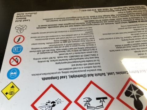 2015 Ford F-550 - A close-up shot of a label for a lead-acid battery, detailing its contents and safety warnings. The label includes hazard symbols and instr…