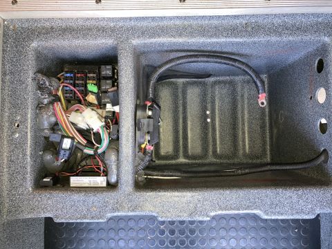 2015 Ford F-550 - A close-up view of a fuse box and wiring harness located in a compartment of a vehicle. The compartment is lined with a textured grey mater…