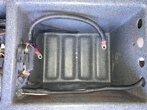 2015 Ford F-550 - A close-up view of a battery box with wiring and a fuse block. The box appears to be a custom installation within a larger compartment.