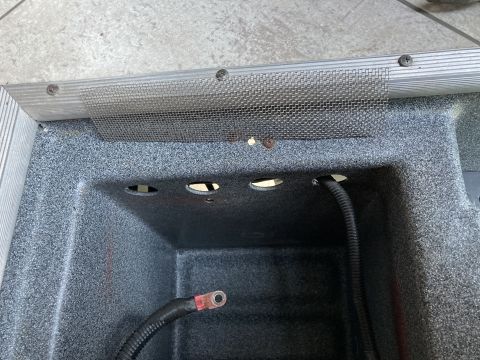 2015 Ford F-550 - A close-up view inside a compartment shows a metal mesh screen secured with screws over a textured surface. Two black electrical cables wit…