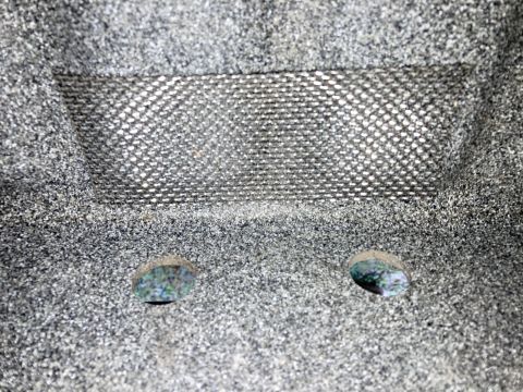 2015 Ford F-550 - A close-up view shows a textured gray surface with a metallic mesh insert and two small circular openings below it. The openings reveal a c…