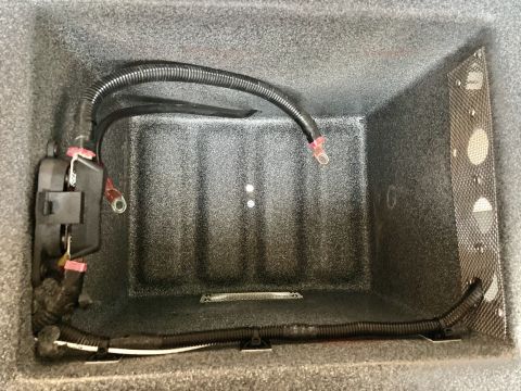 2015 Ford F-550 - The interior of a vehicle's storage compartment shows a black fuse box with red battery cables connected, and a black corrugated wire loom…