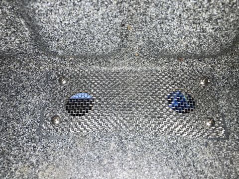 2015 Ford F-550 - A close-up view shows a metallic mesh screen covering two circular openings in a textured, dark gray surface. Four silver rivets secure the…