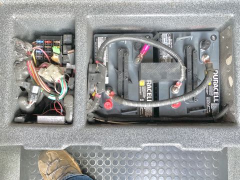 2015 Ford F-550 - Compartment containing house batteries and a fuse box, with a foot visible in the foreground.