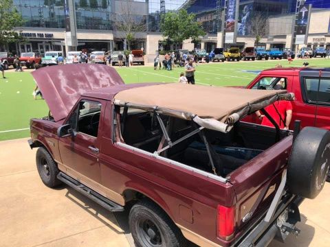 1996 Ford Bronco - A maroon 1996 Ford Bronco is displayed with its hood up and removable top off at a car show.