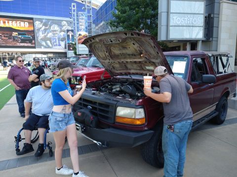 1996 Ford Bronco - People gather around a maroon Ford F-150 pickup truck with its hood open, possibly discussing its engine.