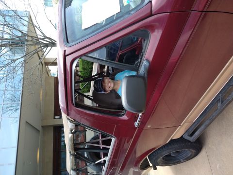 1996 Ford Bronco - A young person smiles from the driver's seat of a red and tan Ford Bronco, with a roll cage visible inside.