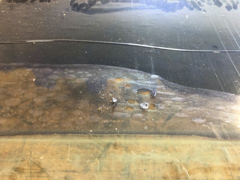 1978 Ford Bronco - This rusted metal part shows significant wear and corrosion, with multiple holes.