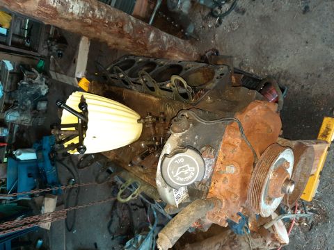 1994 Ford Bronco - An engine block, likely out of a vehicle, is shown in a cluttered workshop environment.