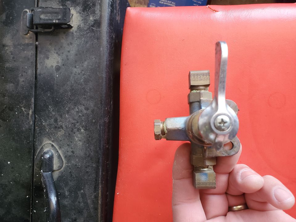 Hand holding a brass valve with a silver lever