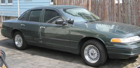 1997 Ford Crown Victoria - A dark green 1997 Ford Crown Victoria sedan is parked outdoors, showing its side profile and front quarter.