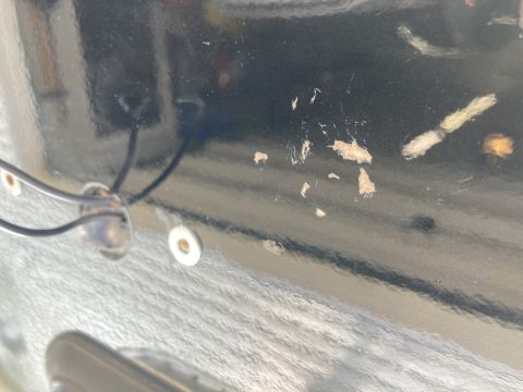 2015 Ford F-550 - A close-up view of the underside of a black vehicle body shows some surface damage and two white grommets with wires passing through them.