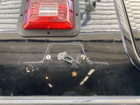 2015 Ford F-550 - A close-up view shows the area below a red taillight assembly on a black vehicle. Exposed wires and mounting holes are visible in a recesse…