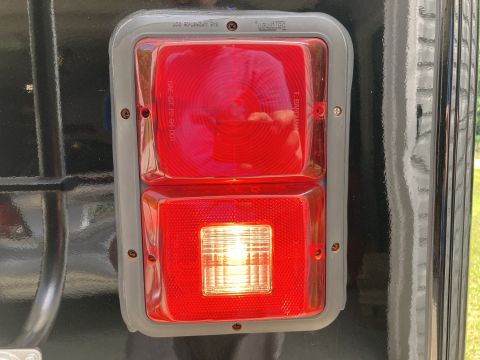 2015 Ford F-550 - A close-up view of a red and clear rectangular taillight assembly mounted on a black vehicle. Text visible on the assembly includes "SAE A2…