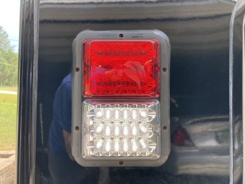 2015 Ford F-550 - A close-up view of the rear trailer lights on a dark-colored vehicle. The lights consist of a red upper section for brake and tail lights a…