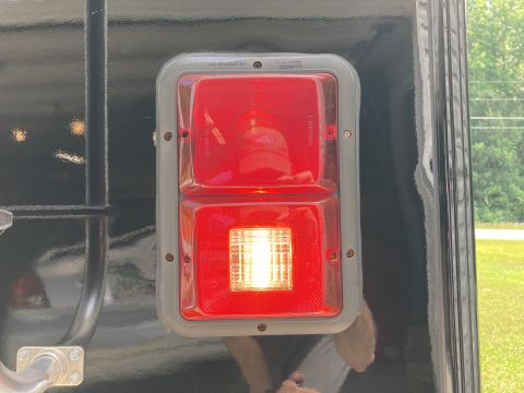 2015 Ford F-550 - A close-up view of a red and clear rectangular trailer light assembly mounted on a black vehicle. The assembly has two sections: the top se…