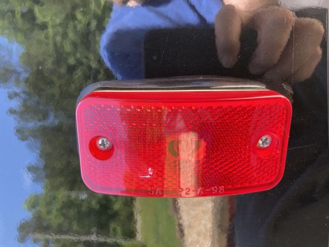 2015 Ford F-550 - A close-up shot of a red rectangular reflector with "SAE-P2-A-98" embossed on the bottom edge. The reflector is mounted on a shiny black su…