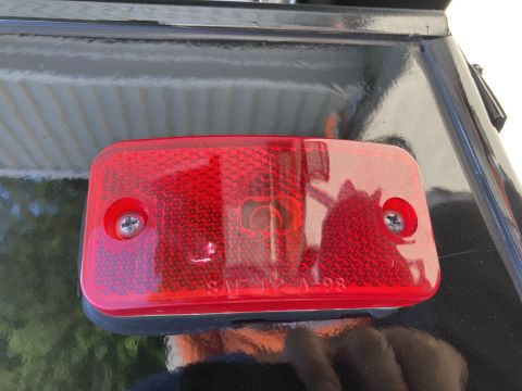 2015 Ford F-550 - A red rectangular reflector is attached to a black surface with two silver screws. Text on the reflector reads "SAE T2A 98".
