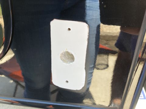 2015 Ford F-550 - A close-up view of a white rectangular plate with two small holes and one larger central hole, attached to a dark, reflective surface, poss…