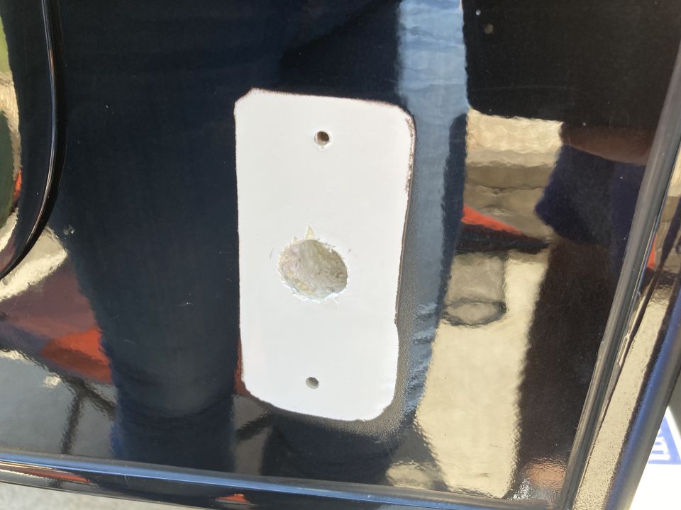 White plate with holes attached to a dark reflective surface.
