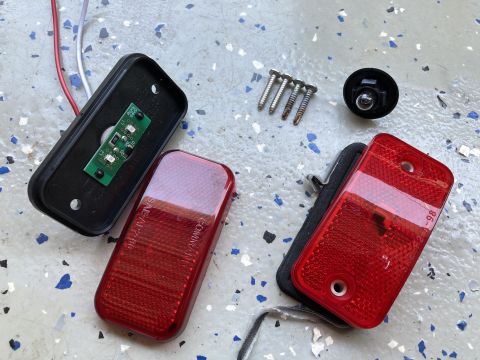 2015 Ford F-550 - Disassembled red LED trailer lights are laid out on a speckled gray surface. Components include two red lenses, a black housing with a circ…