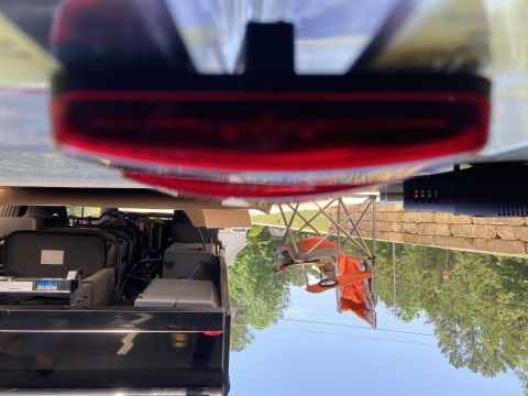 2015 Ford F-550 - The underside of a red taillight is visible above a black storage compartment containing various components and a Reese label. A portion of…